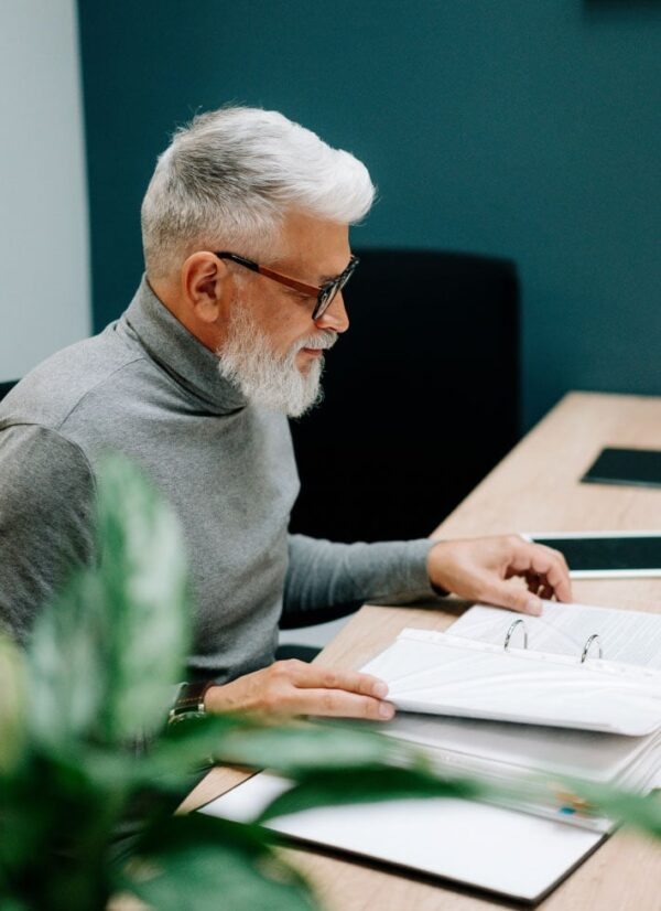 Man with glasses at a desk reading a folder about leadership development programs