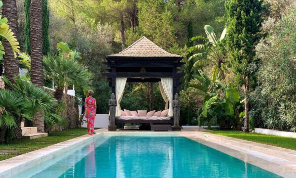 Woman in pink floral dress walking towards a daybed by the pool at the retreat in Ibiza